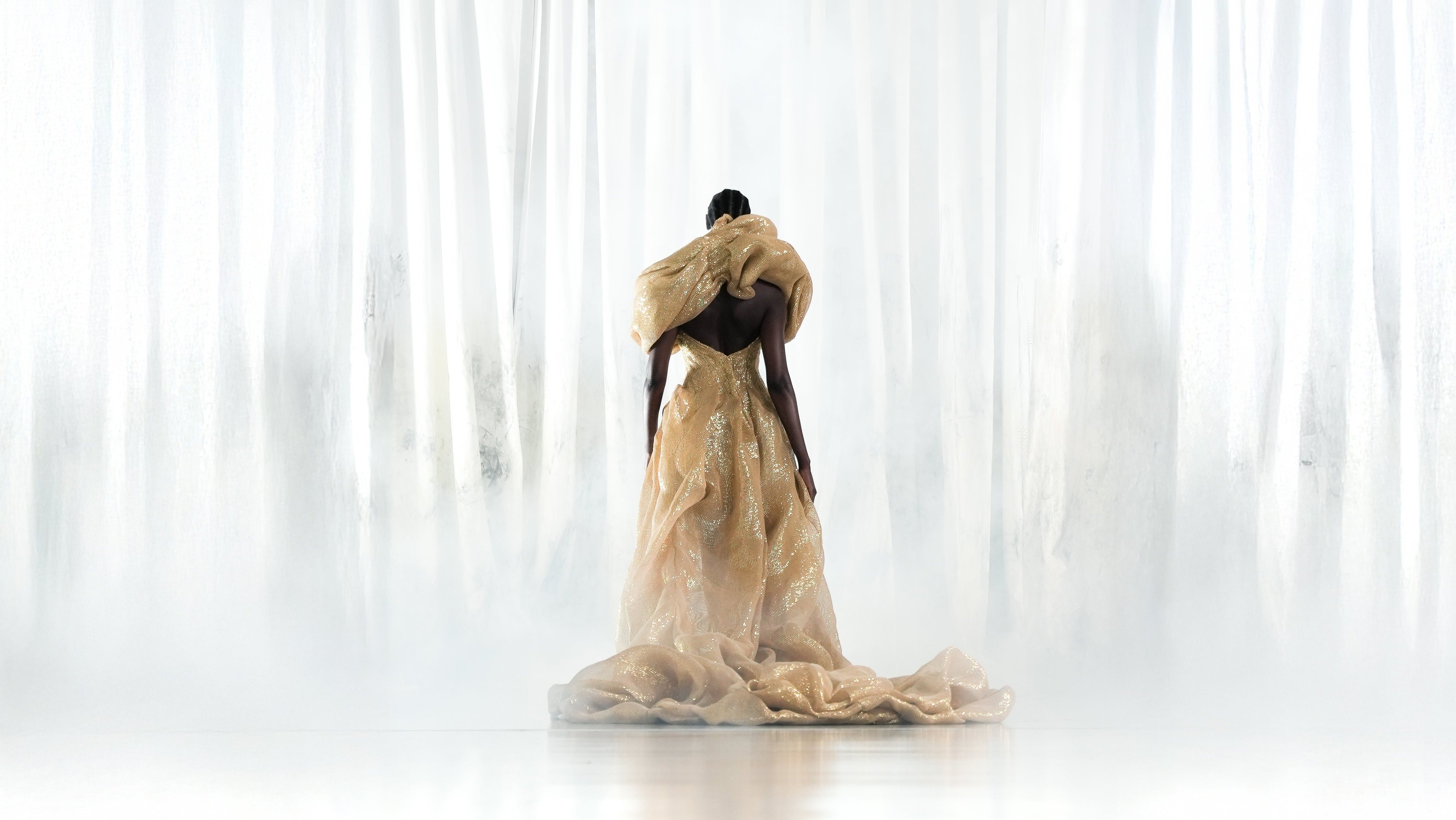 Woman wearing a long, flowing golden dress with voluminous material