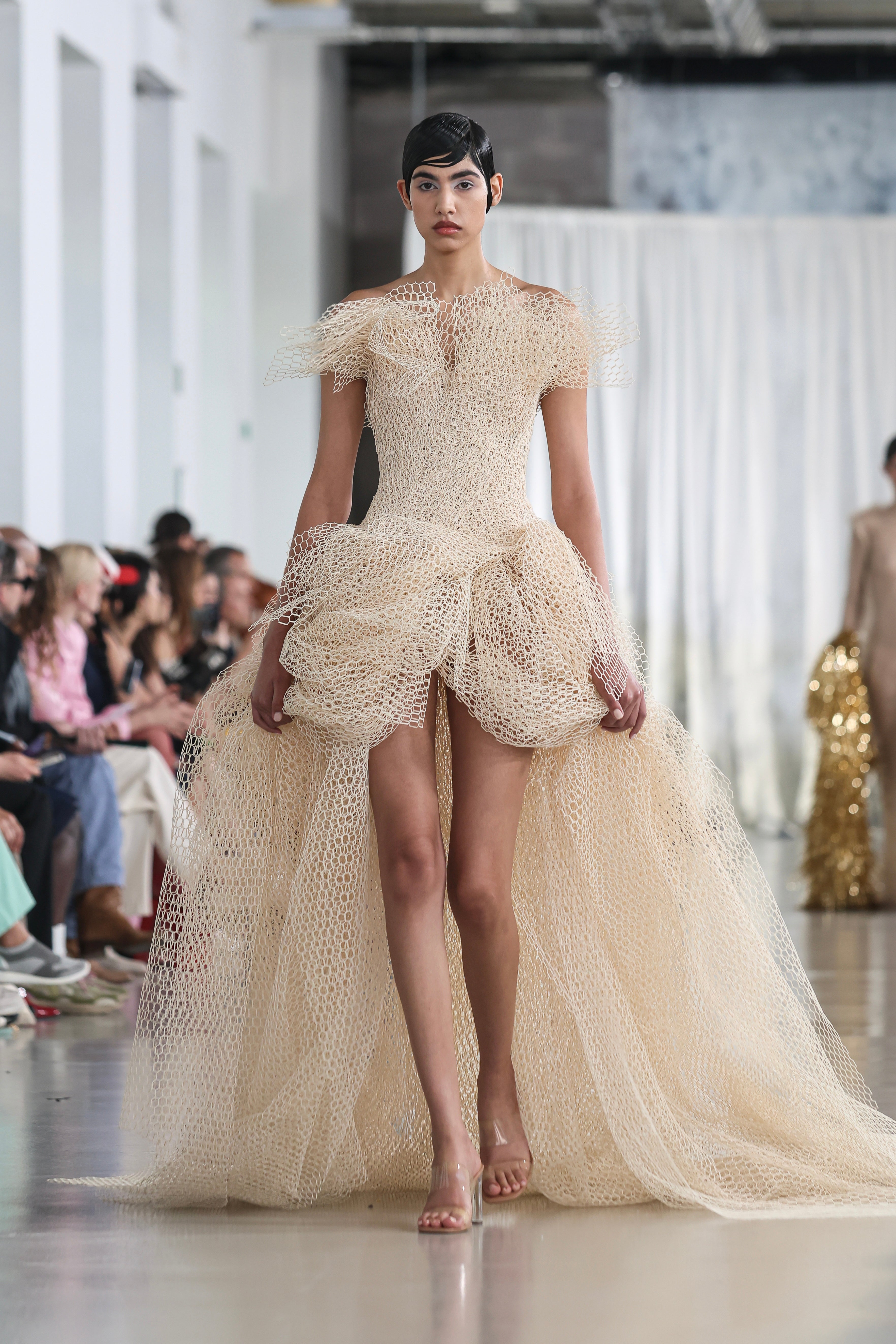 Model in off-shoulder beige gown crafted from sculpted straw-effect material 